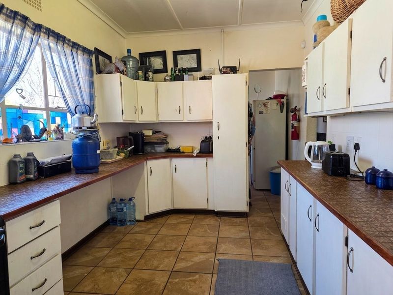 A functional kitchen featuring laminate countertops, tiled flooring, and ample built-in cabinetry, offering a dated aesthetic ready for modernization.