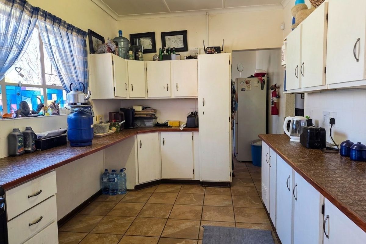 A functional kitchen featuring laminate countertops, tiled flooring, and ample built-in cabinetry, offering a dated aesthetic ready for modernization.