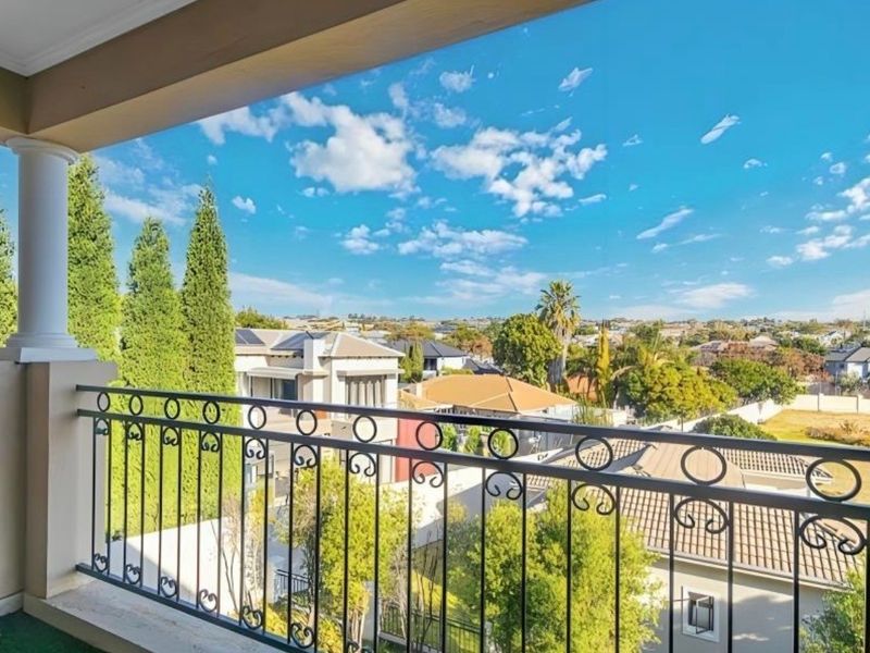 A spacious covered balcony featuring a decorative wrought iron balustrade and offering expansive elevated views of the surrounding residential neighborhood.