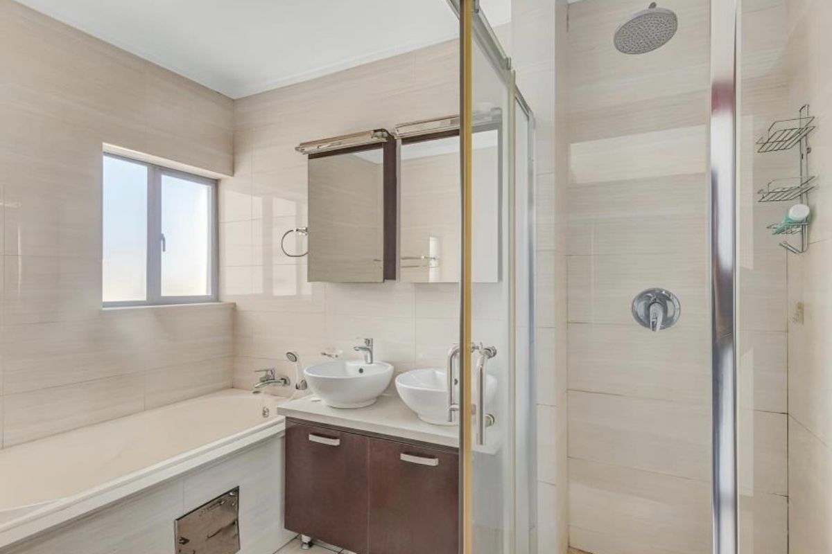 Modern bathroom featuring a double vanity with vessel sinks, a built-in bathtub, and a separate glass-enclosed shower with a rain shower head.