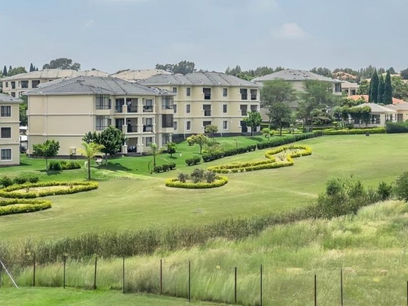 An elevated view of a well-maintained residential apartment complex surrounded by landscaped communal gardens and green spaces.