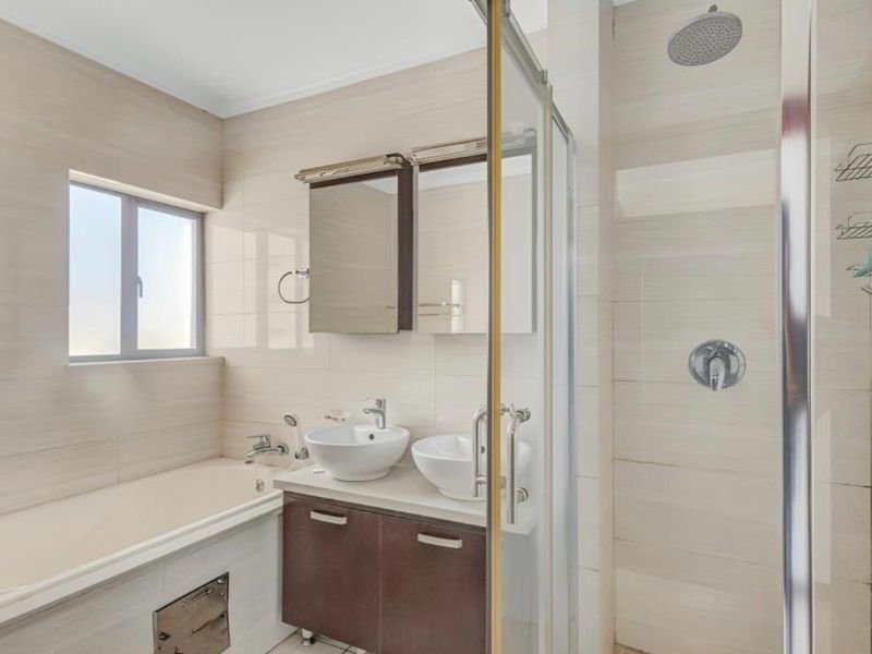 Modern bathroom featuring a double vanity with vessel sinks, a built-in bathtub, and a separate glass-enclosed shower with a rain shower head.