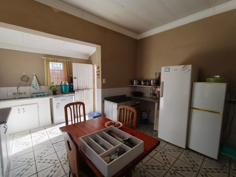 Open-plan kitchen and dining area featuring tiled flooring, built-in cabinetry, and a freestanding stove, offering a functional space with potential for modernization.