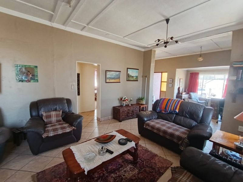 Spacious living area featuring tiled flooring and traditional ceiling panels, offering a functional layout with potential for cosmetic updates.