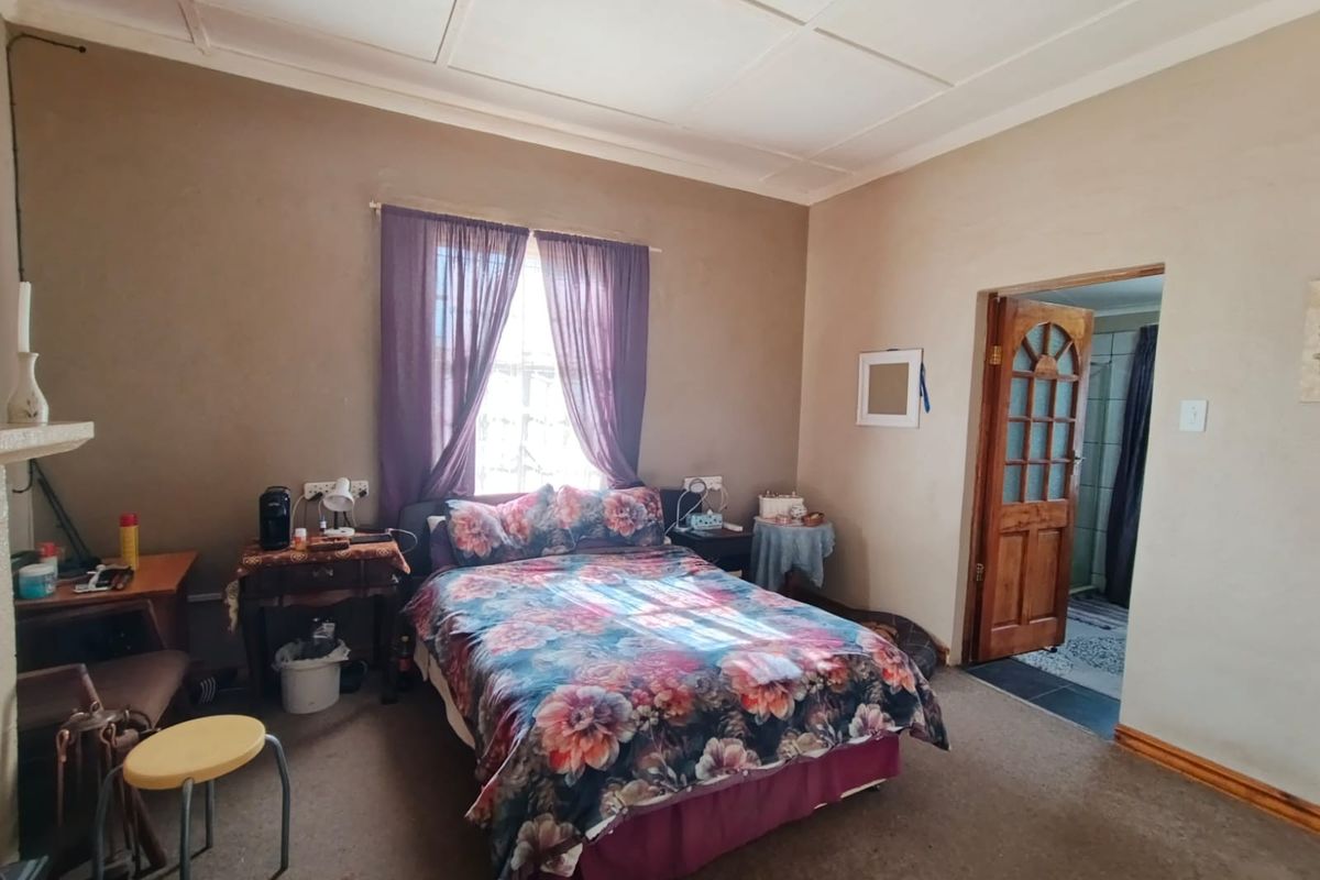 A bedroom featuring carpet flooring, a timber door leading to an en-suite, and a window with natural light.
