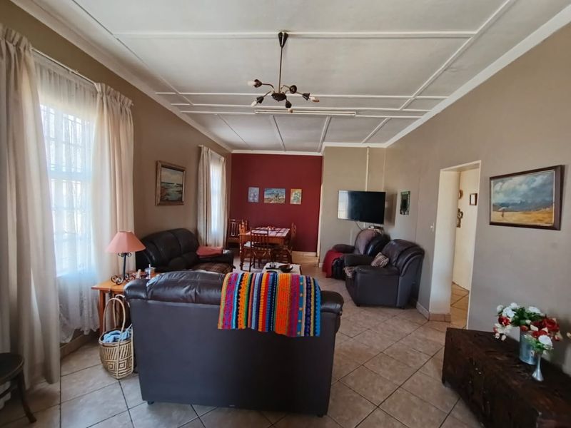 An open-plan living and dining area featuring tiled flooring and decorative ceiling panels, providing a functional space for relaxation and meals.