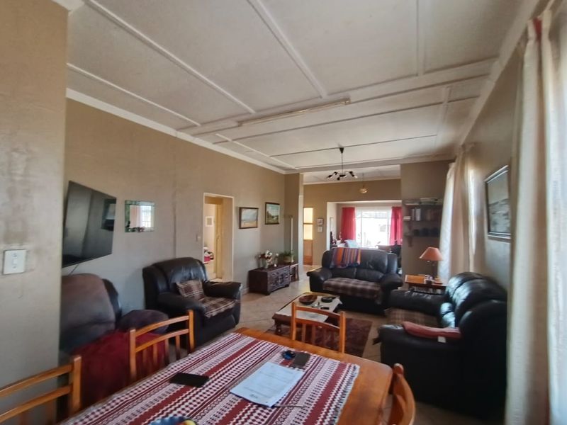 Spacious open-plan living and dining area featuring tiled flooring and a panelled ceiling, offering a versatile layout for family living.