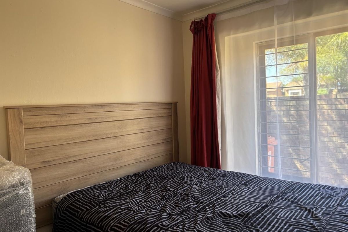 A bedroom featuring a sliding glass door with security bars, providing natural light and access to the exterior.