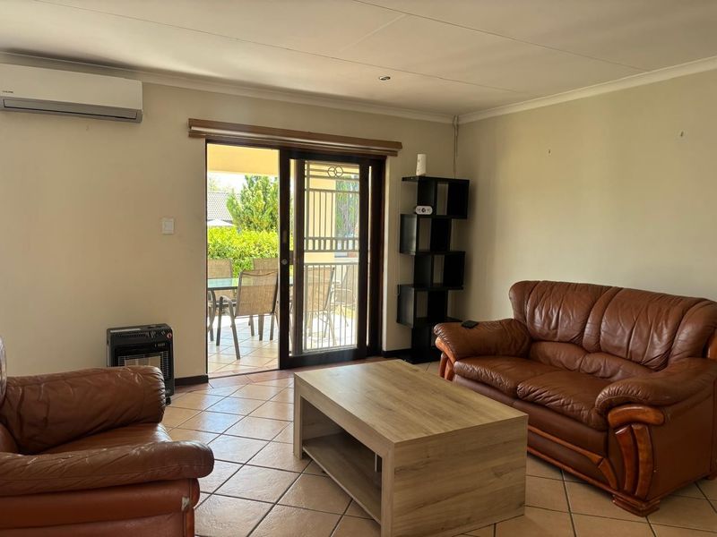 A living room featuring tiled flooring, an air conditioning unit, and a sliding glass door providing access to an outdoor patio area.