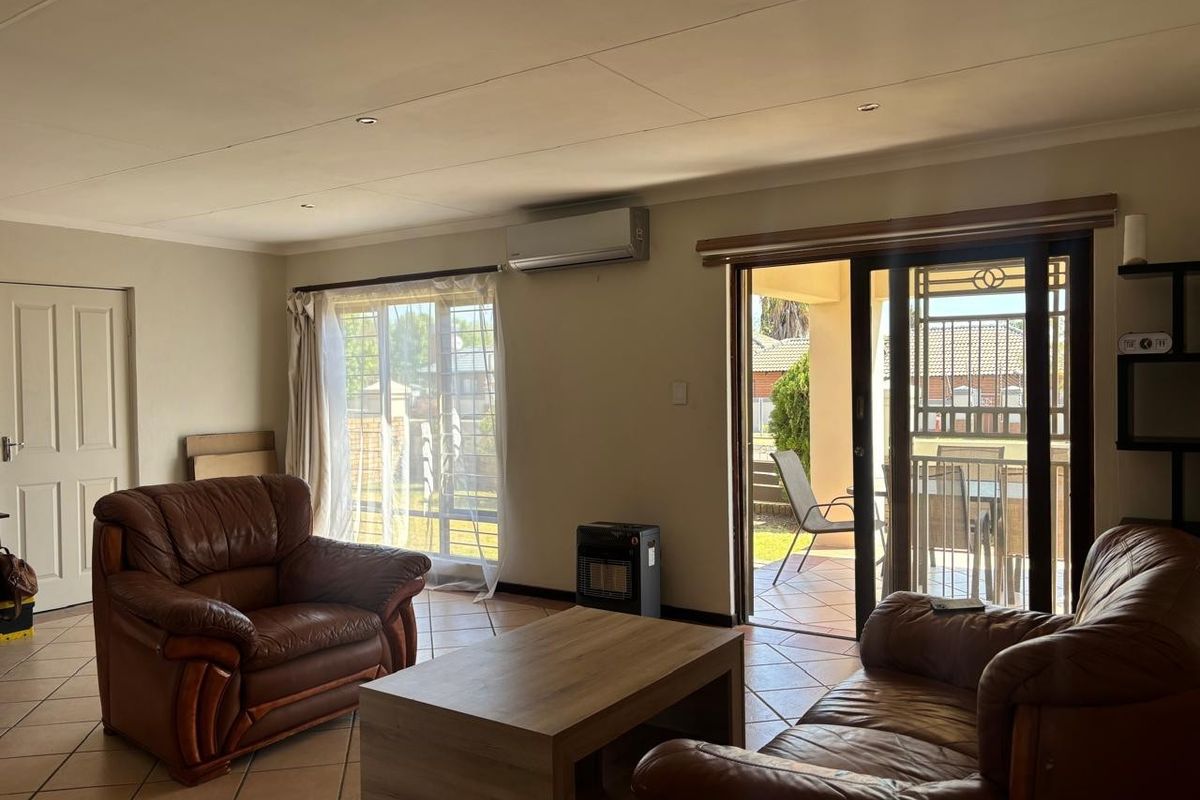 A living room featuring tiled flooring, recessed lighting, an air conditioning unit, and sliding glass doors providing access to an outdoor patio area.