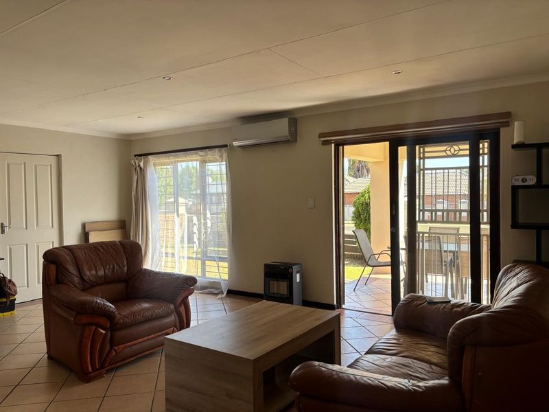 A living room featuring tiled flooring, recessed lighting, an air conditioning unit, and sliding glass doors providing access to an outdoor patio area.