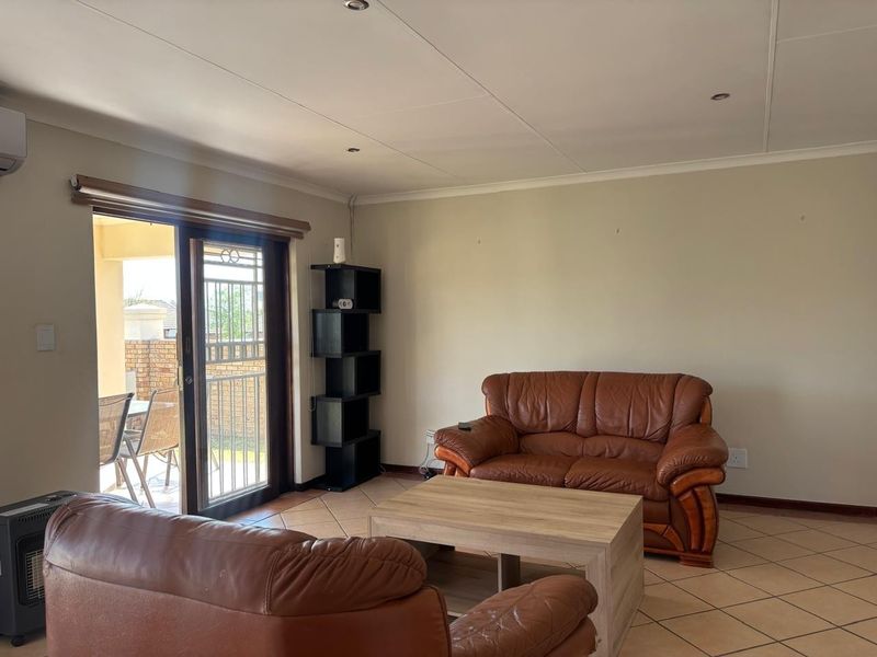 A living room featuring tiled flooring, recessed lighting, and a sliding glass door providing access to an outdoor patio area.