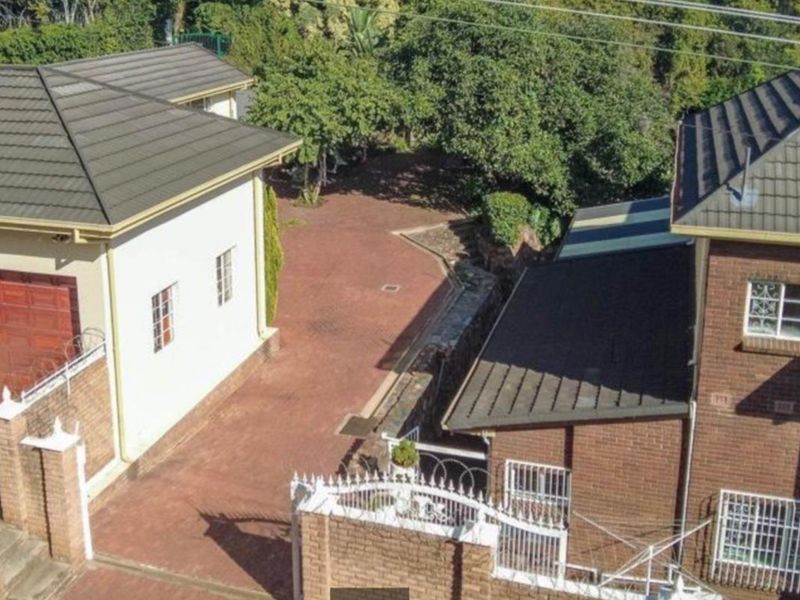 Aerial view of the commercial property showing the paved driveway, brick building structures, tiled roofing, and perimeter security fencing.