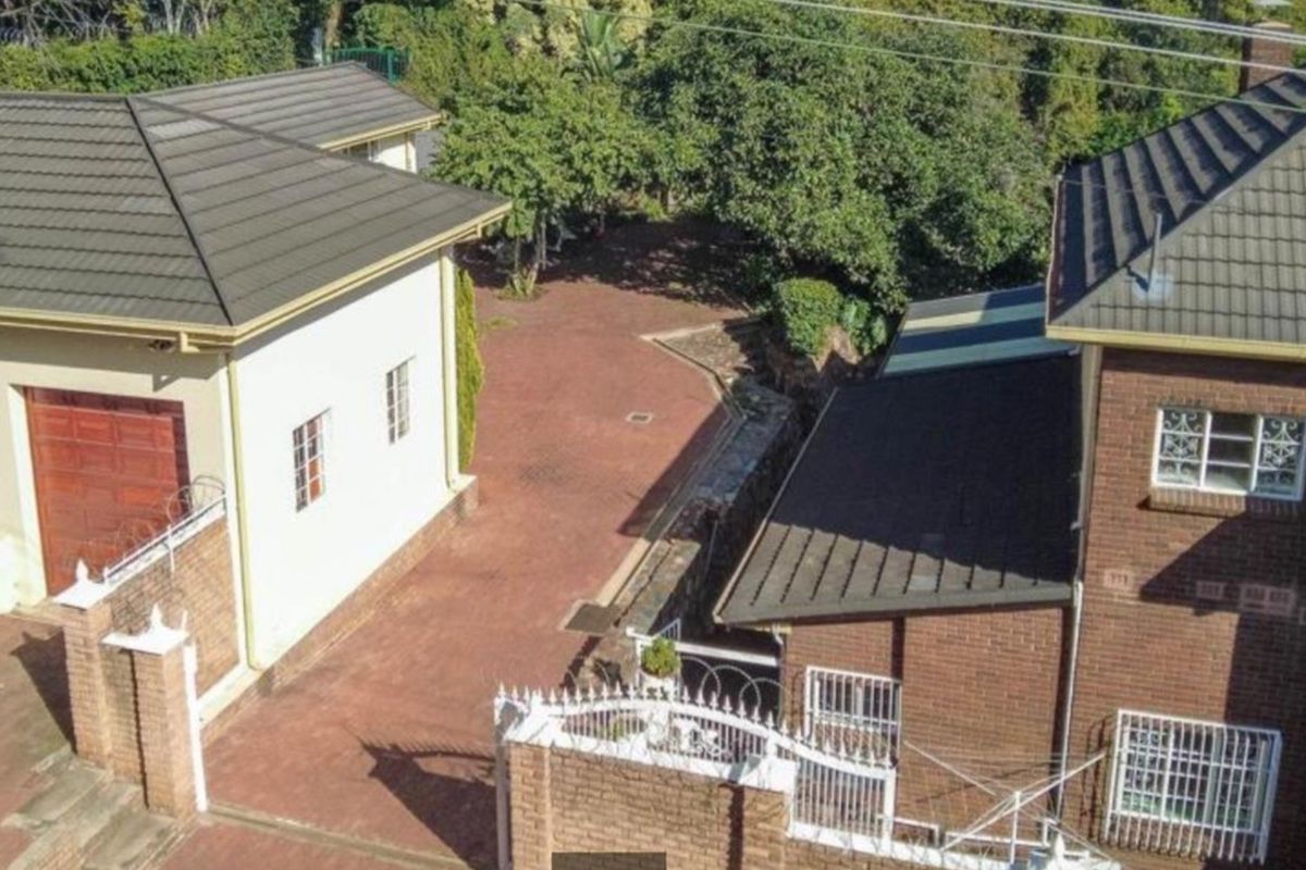 Aerial view of the commercial property showing the paved driveway, brick building structures, tiled roofing, and perimeter security fencing.