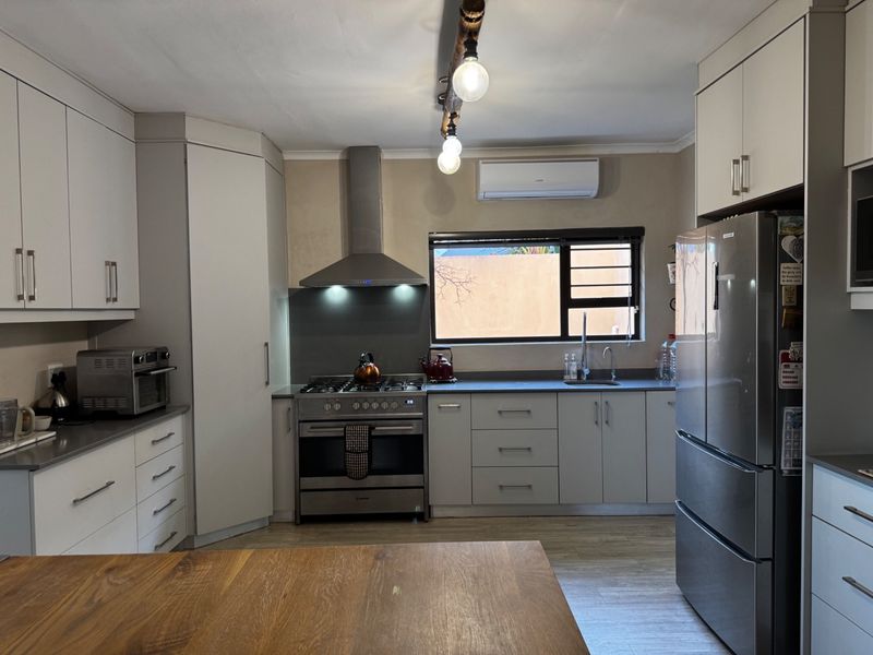 A well-maintained kitchen featuring modern cabinetry, a gas stove with stainless steel extractor, and a split-system air conditioner.