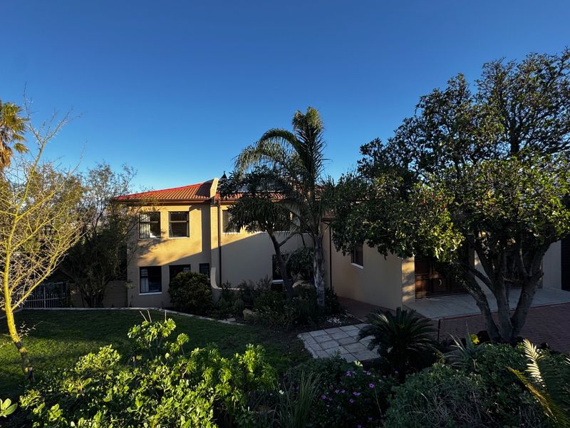 A well-maintained double-storey residential property featuring a tiled roof, paved driveway, and established garden surroundings.