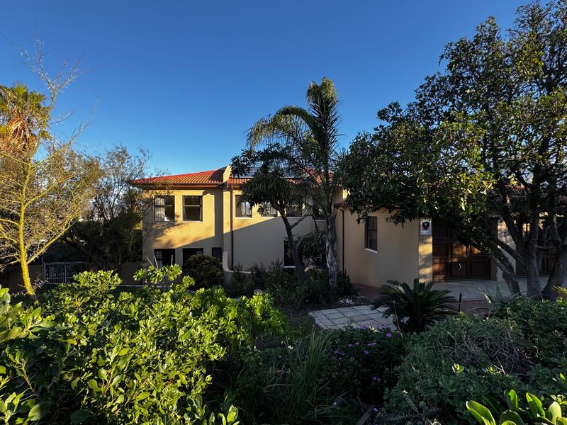 Front elevation of a two-story residential house featuring a tiled roof, garage access, and established garden landscaping.