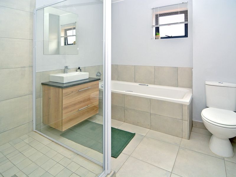 Modern bathroom featuring a floating vanity with vessel sink, a built-in bathtub, and a separate glass-enclosed shower with neutral tiling.