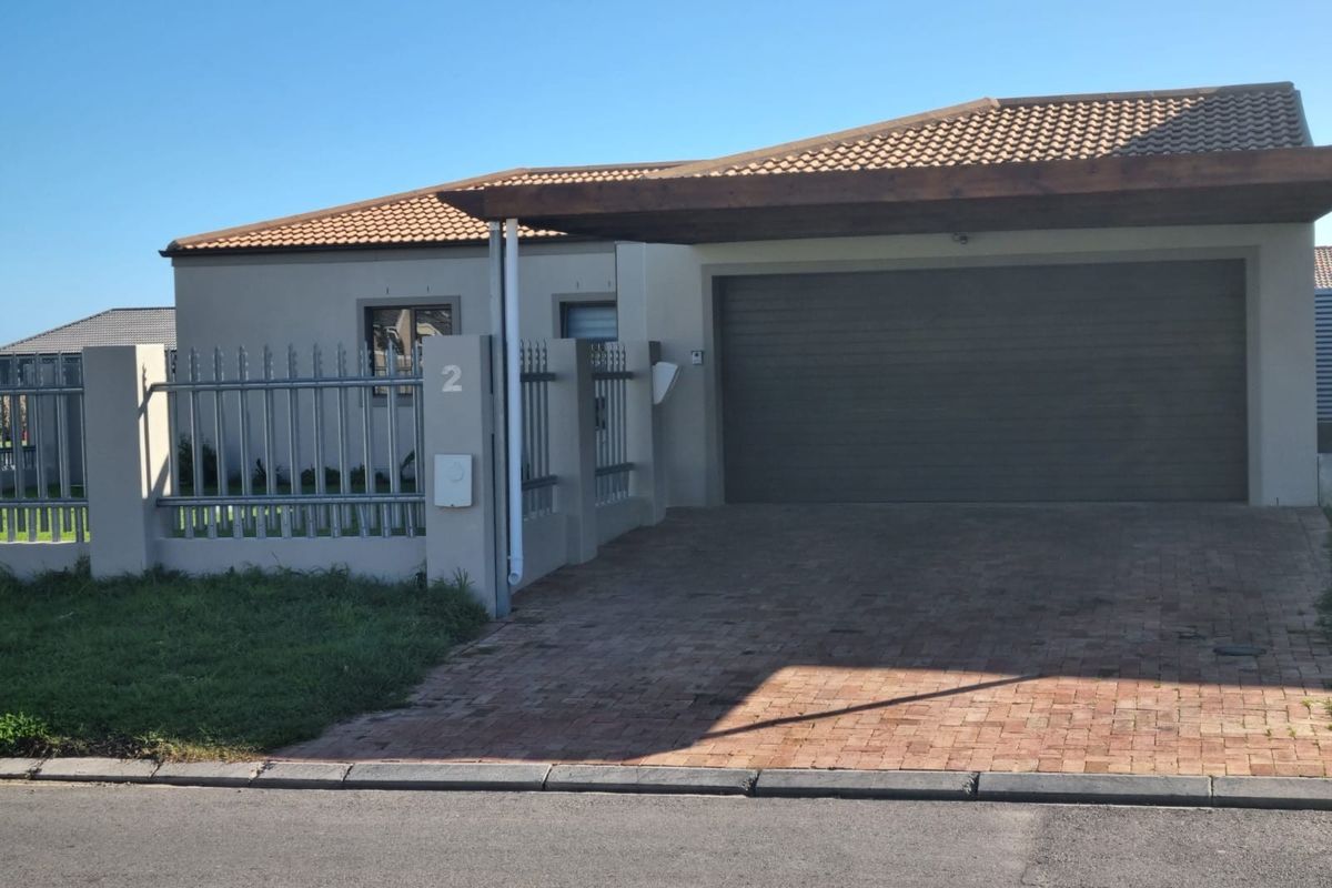 Front exterior view of the property featuring a paved driveway, covered carport, garage, and secure metal perimeter fencing.