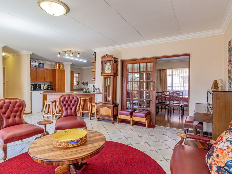 Spacious open-plan living area featuring tiled floors, a functional kitchen with island, and sliding glass doors leading to an adjacent dining space.