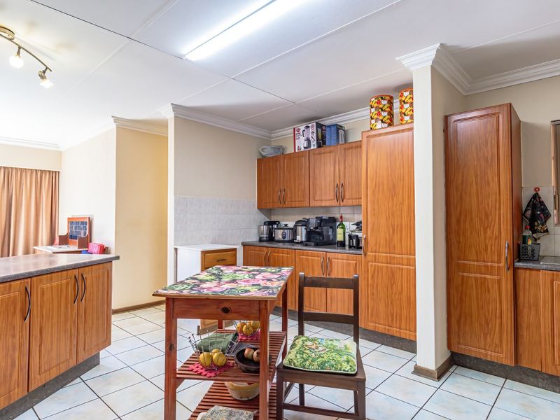 A functional kitchen featuring wood-look laminate cabinetry, tiled flooring, and ample storage space, offering a classic layout ready for modern updates.