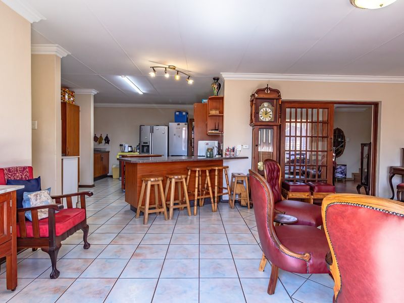 Open plan living and kitchen area featuring tiled flooring, a central kitchen island, and access to an adjacent room through a wooden sliding door.
