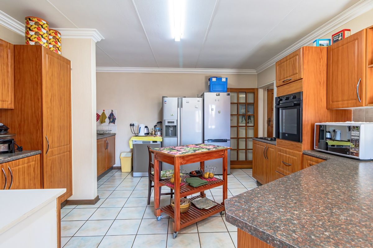 A functional kitchen featuring wood-finish cabinetry, laminate countertops, built-in oven, and tiled flooring with ample space for appliances.