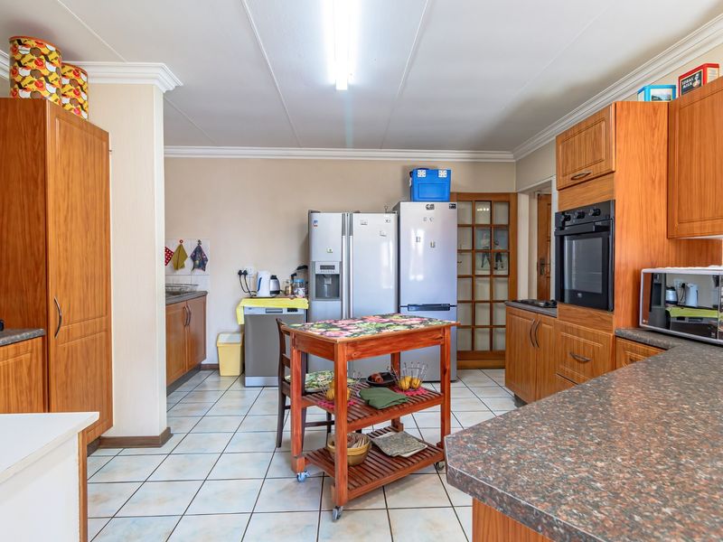 A functional kitchen featuring wood-finish cabinetry, laminate countertops, built-in oven, and tiled flooring with ample space for appliances.