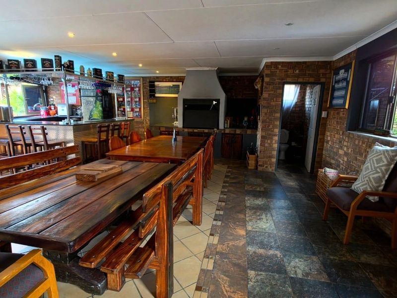 Spacious open-plan entertainment area featuring a built-in bar, indoor braai, exposed brick walls, and durable tiled flooring, ideal for hosting guests.