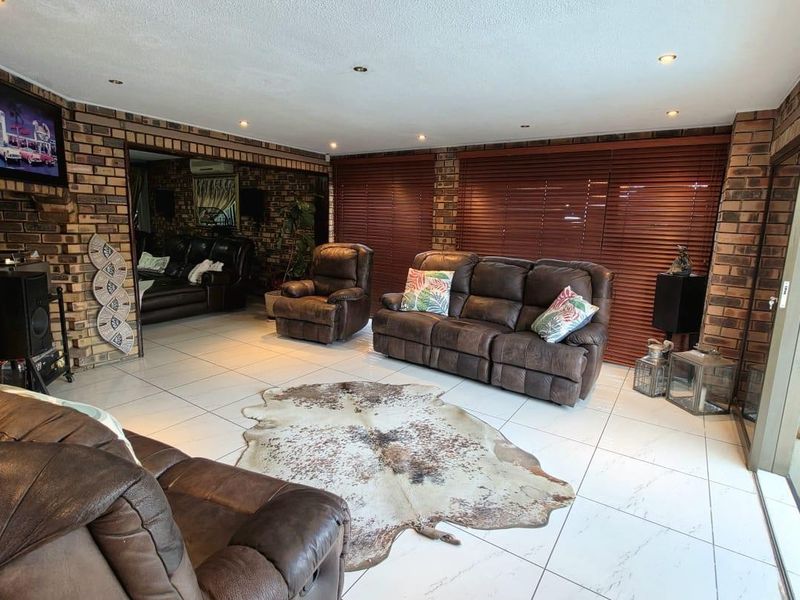 Spacious living room featuring exposed brick walls, large format floor tiles, recessed lighting, and sliding glass doors providing access to the outdoor area.