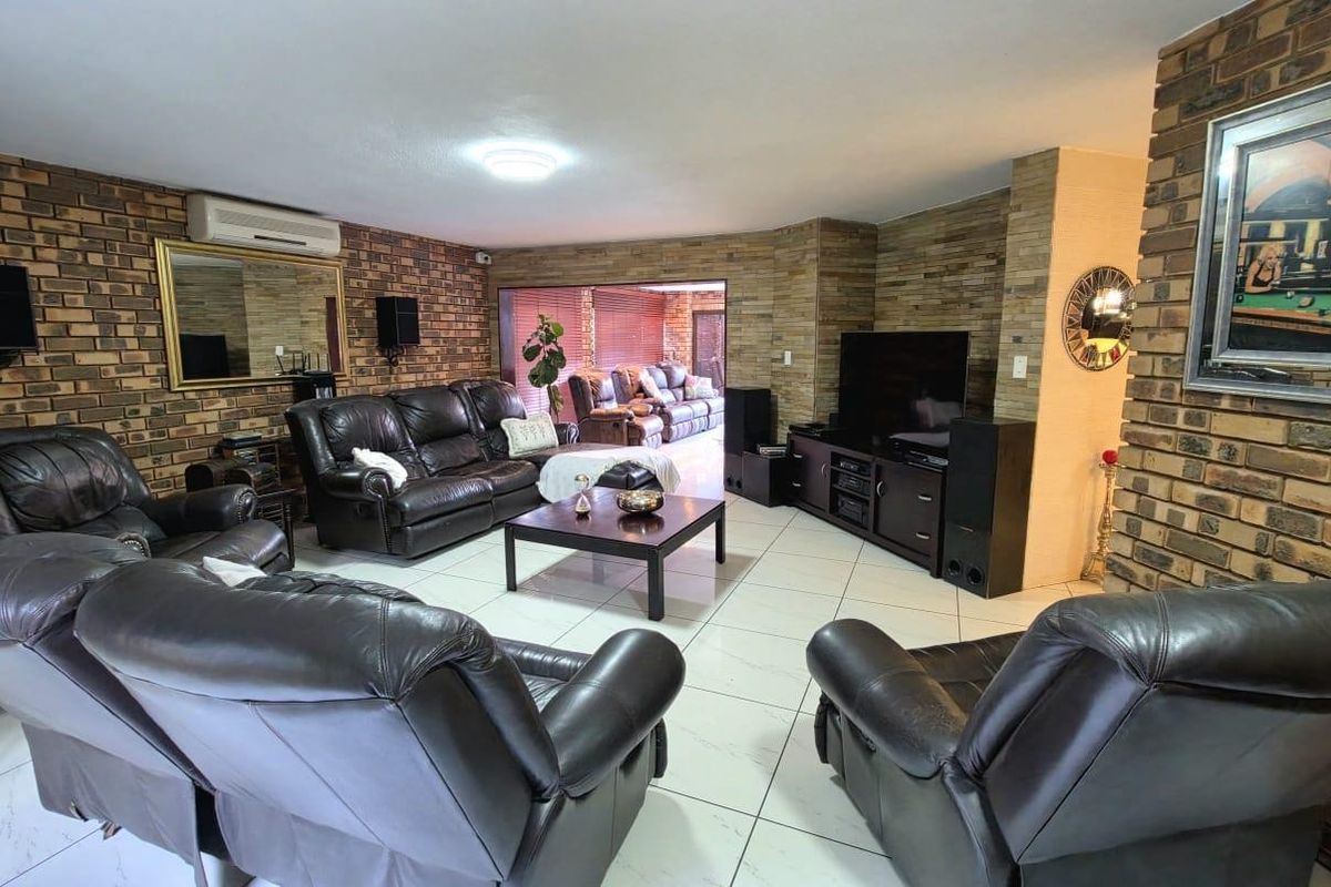 Spacious living room featuring exposed brick walls, stone feature wall, and tiled flooring, with direct access to an adjoining patio area.