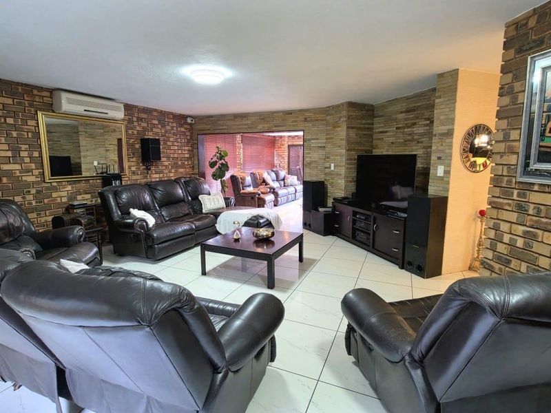 Spacious living room featuring exposed brick walls, stone feature wall, and tiled flooring, with direct access to an adjoining patio area.
