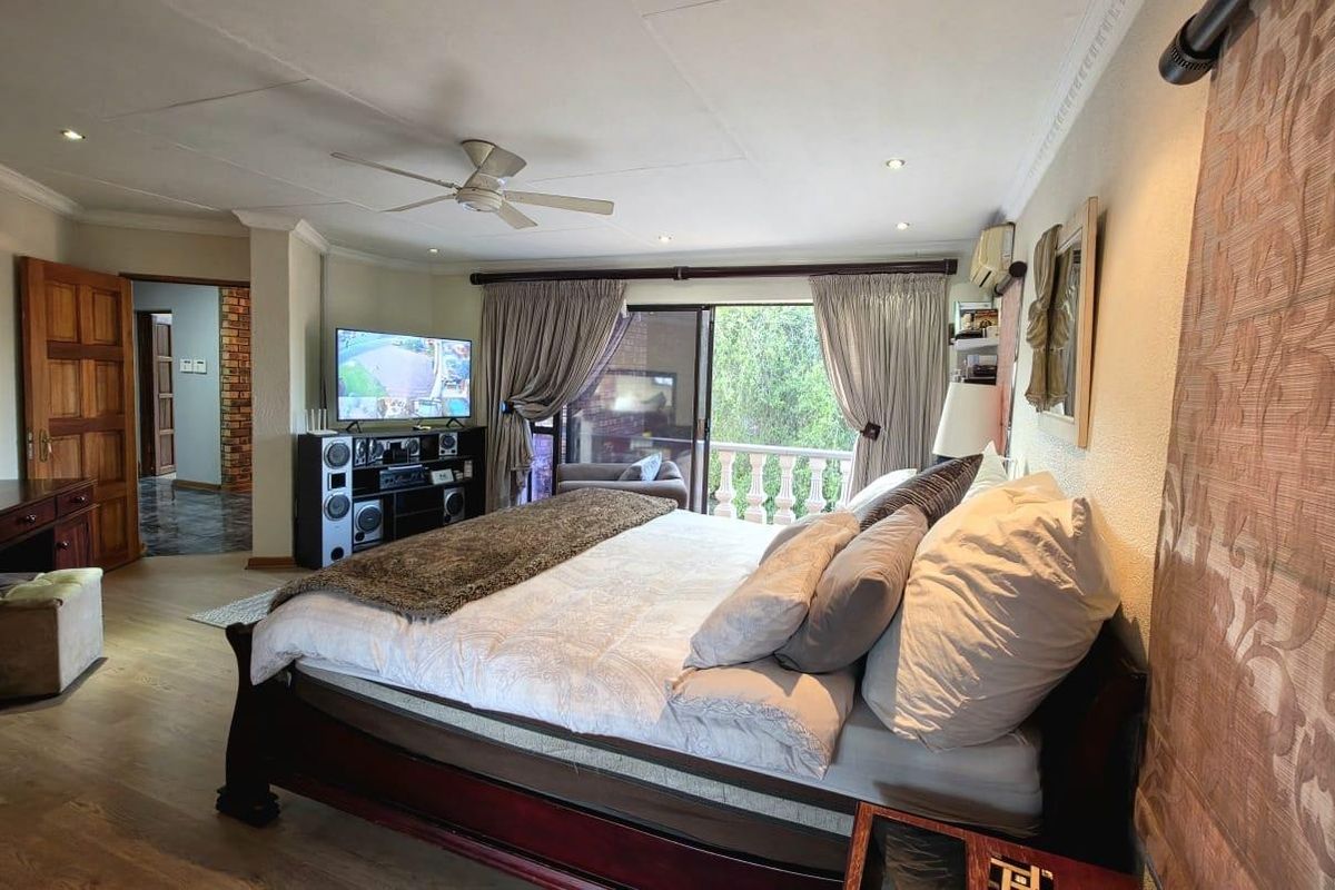 Spacious bedroom featuring laminate flooring, crown molding, a ceiling fan, and direct access to a private balcony through sliding glass doors.
