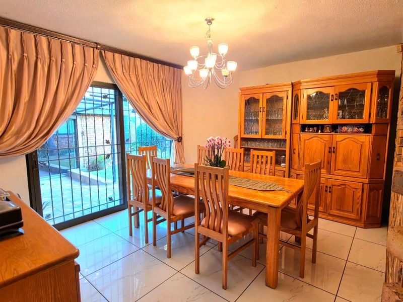 A dining room featuring tiled flooring, an exposed brick wall, and a sliding glass door providing access to the outdoor area.