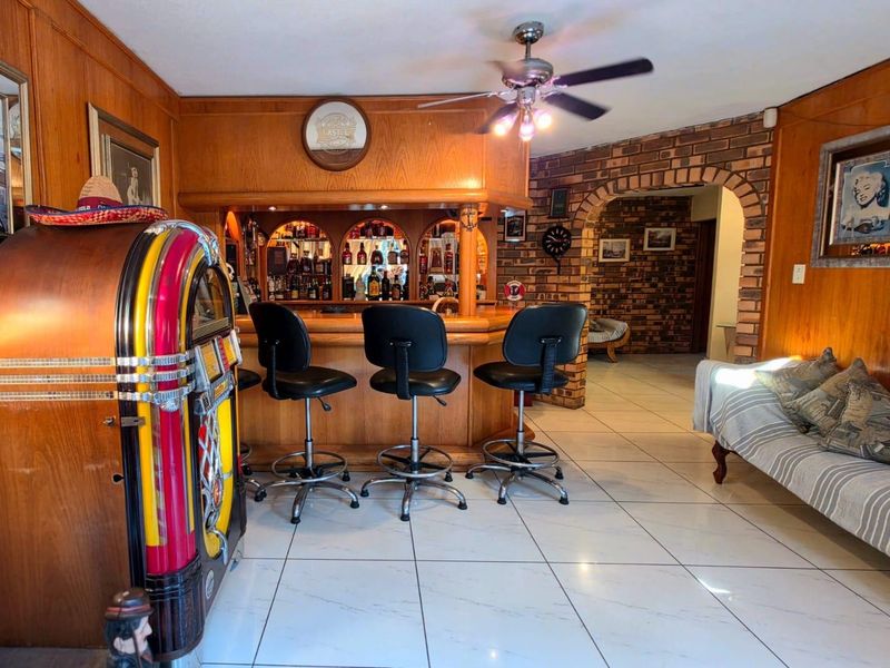 A dedicated bar area featuring a built-in wooden counter, brick archway architectural detail, wood-paneled walls, and tiled flooring.