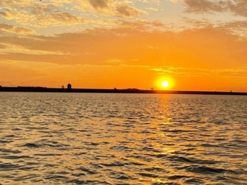 A scenic sunset view over the water, highlighting the natural landscape and horizon.