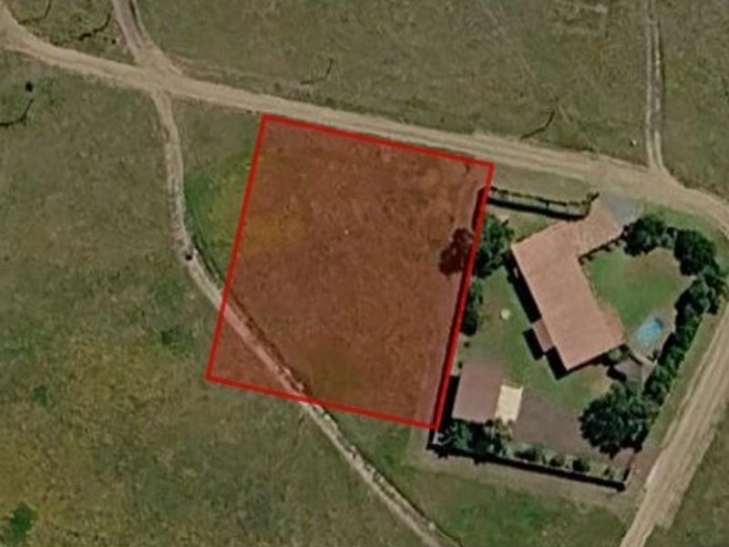 An aerial view of a vacant residential land parcel with red boundary lines indicating the property perimeter.