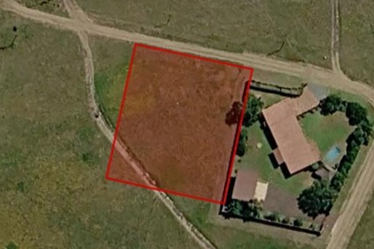 An aerial view of a vacant residential land parcel with red boundary lines indicating the property perimeter.