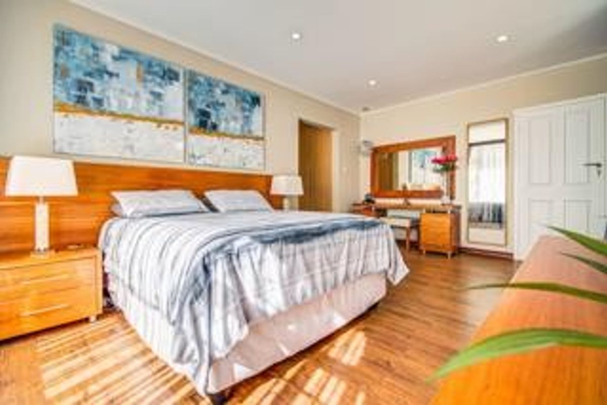 A well-maintained bedroom featuring laminate flooring, recessed downlighting, and a built-in vanity area with integrated mirror.