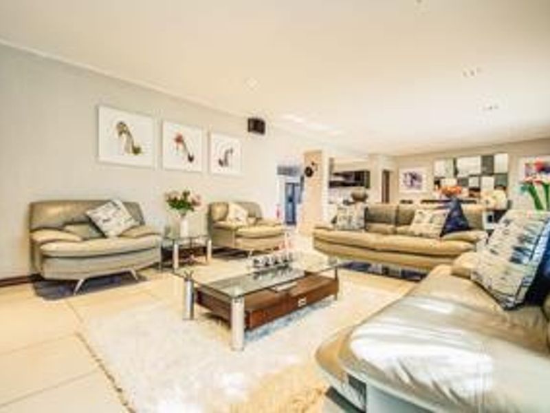 Spacious open-plan living area featuring tiled flooring, recessed lighting, and a seamless flow into the adjacent kitchen space.