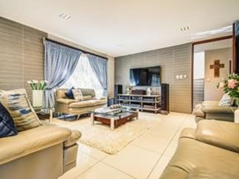 Spacious living room featuring large format floor tiles, recessed downlighting, and a textured feature wall, creating a comfortable and well-maintained lounge area.
