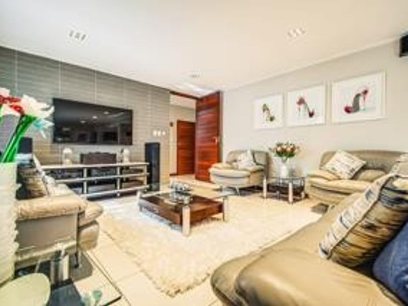 A well-maintained living room featuring a textured feature wall, tiled flooring, and recessed downlighting, creating a comfortable and inviting space.