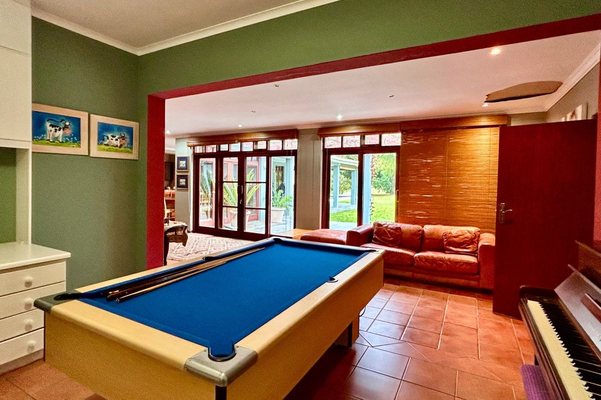 Spacious living area featuring terracotta floor tiles, recessed lighting, and large timber-framed glass doors providing access to the outdoor patio area.