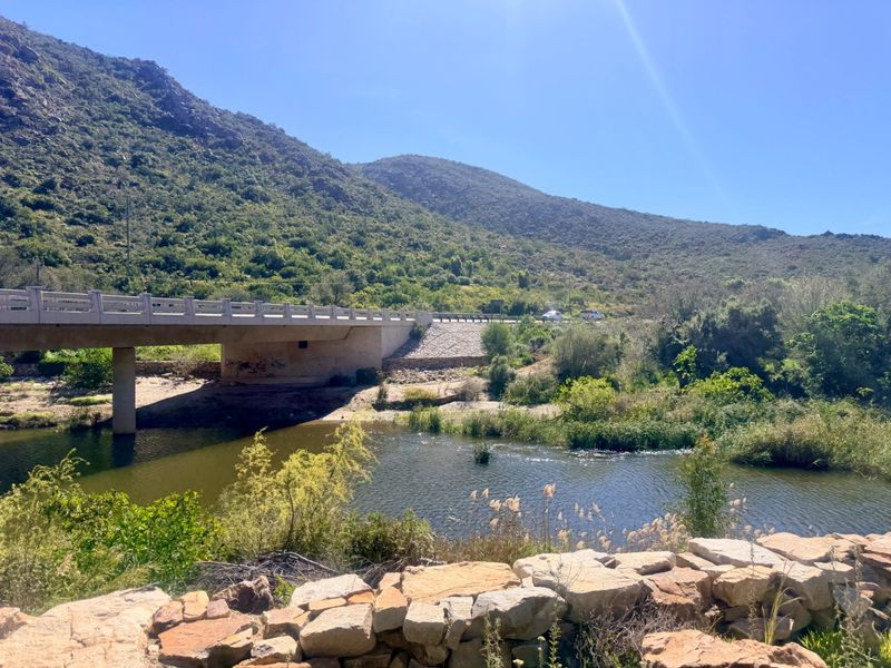 Scenic landscape view featuring a river, a concrete bridge, and natural mountain terrain.