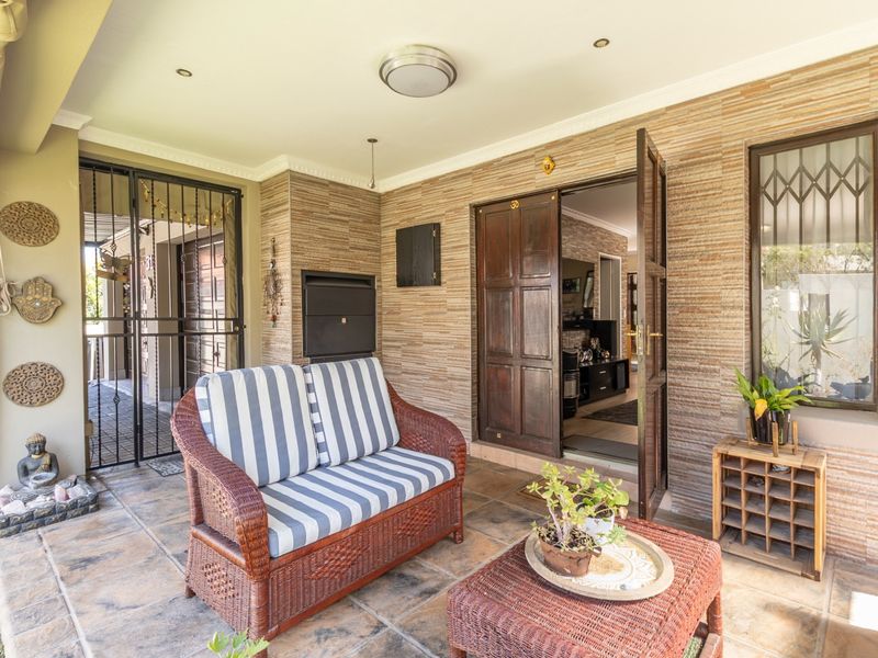 Covered patio area featuring stone-clad walls, tiled flooring, and a built-in braai, providing a functional outdoor entertainment space.
