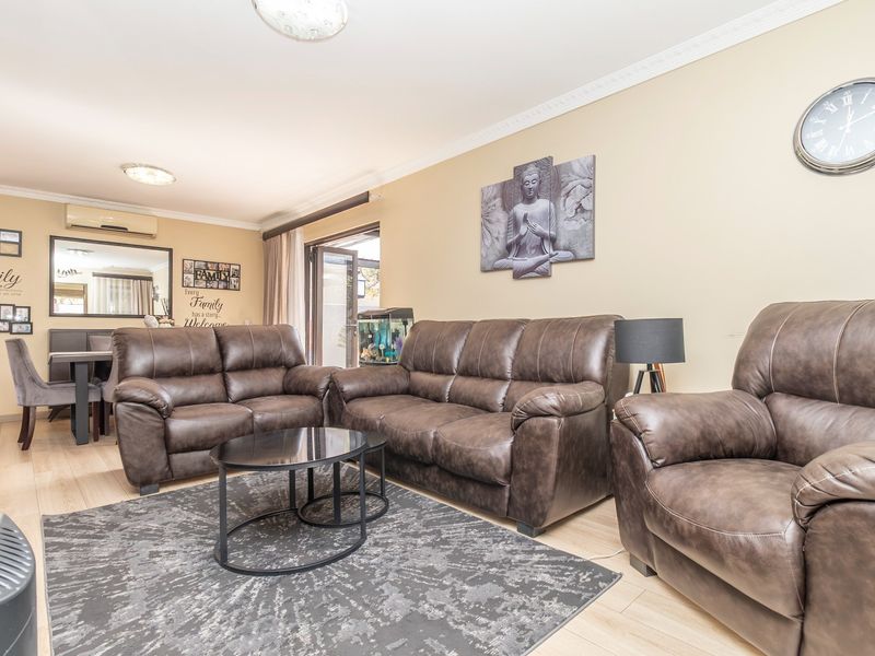 A well-maintained living room featuring laminate flooring, coving, and a sliding glass door providing access to the outdoor area.