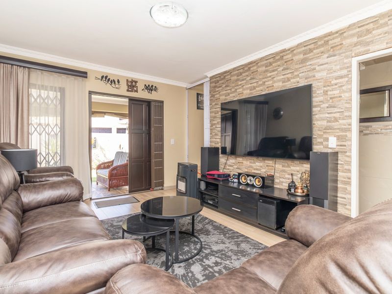 A comfortable living room featuring a textured stone veneer accent wall, laminate flooring, and direct access to an outdoor patio area.