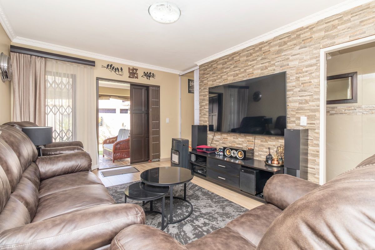 A comfortable living room featuring a textured stone veneer accent wall, laminate flooring, and direct access to an outdoor patio area.