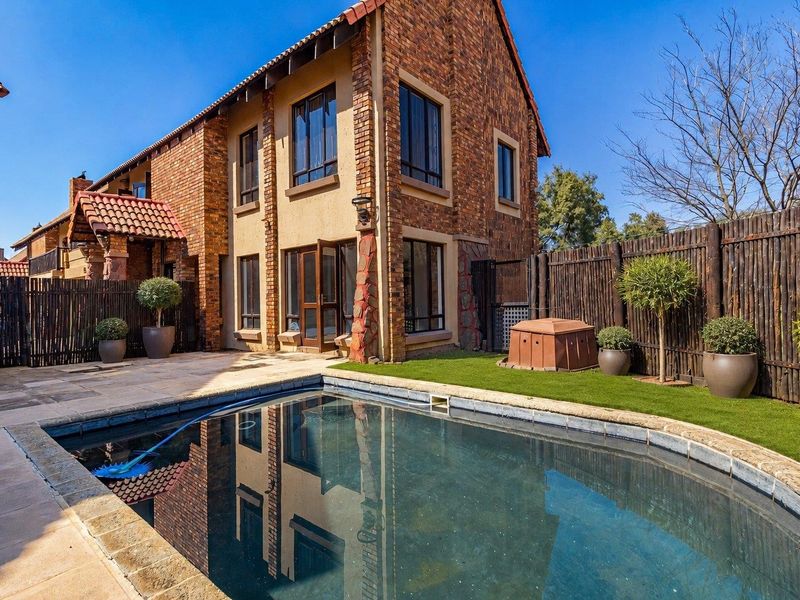Rear exterior view of the townhouse featuring a private swimming pool, paved patio area, and well-maintained garden with timber fencing.