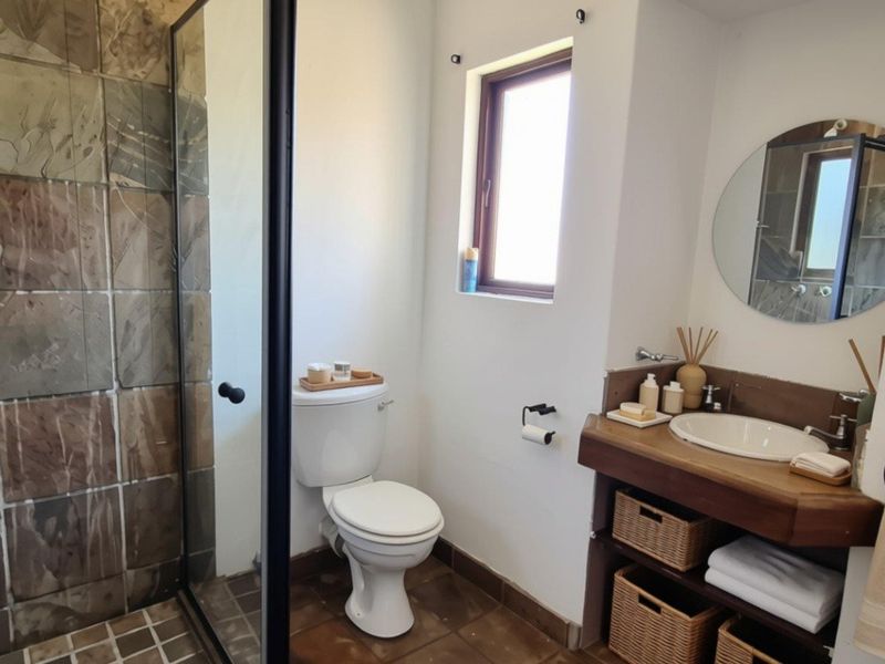 A well-maintained bathroom featuring a walk-in shower with stone tiling, a wooden vanity with integrated basin, and a modern glass shower enclosure.